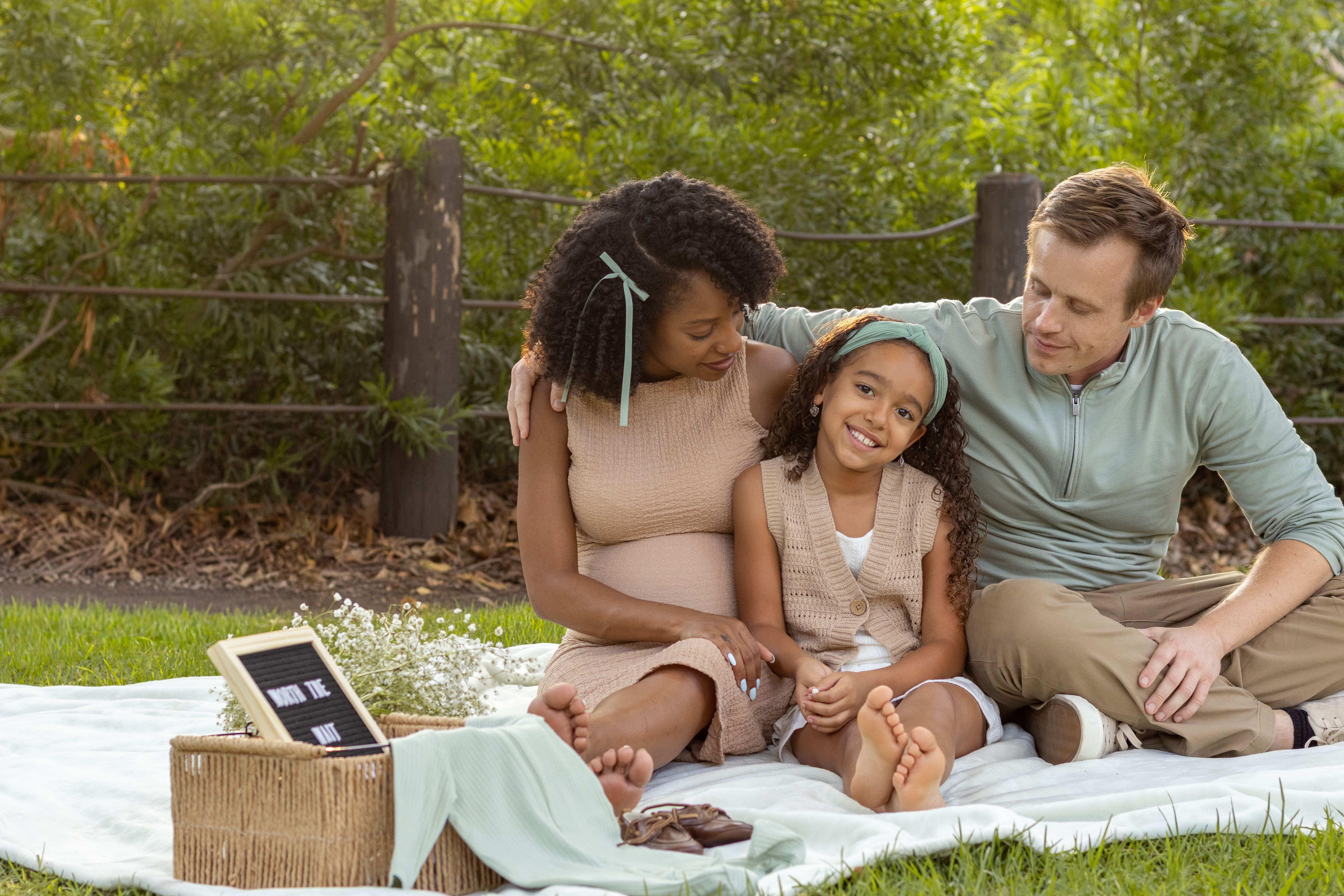 Jess, Nia, and Theo sitting together on a picnic blanket outdoors