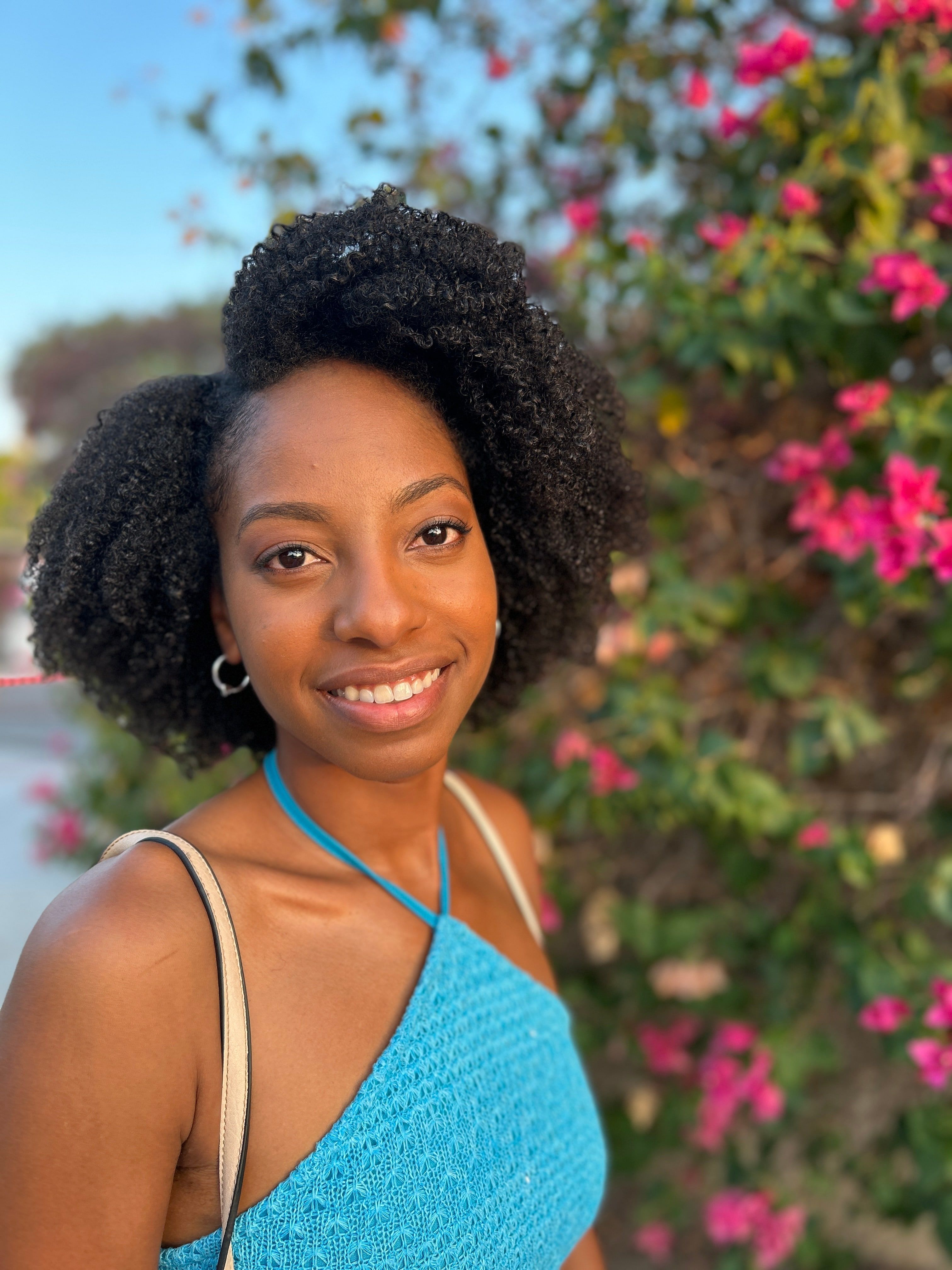 Jessika smiling outside by flowering greenery