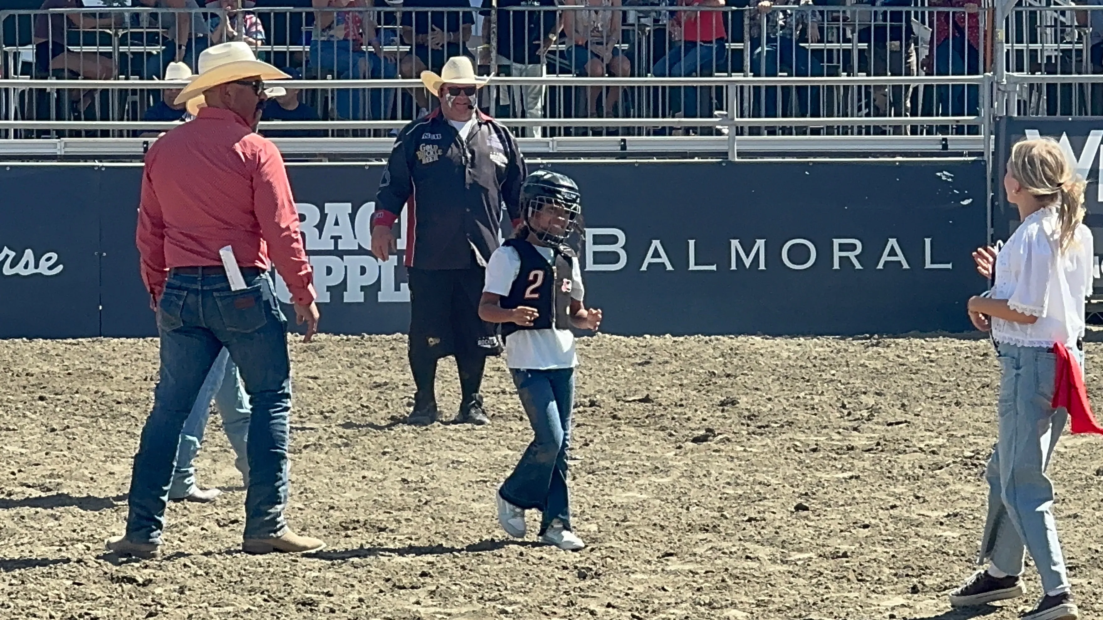Niabelle in a helmet and #2 jersey walking across the arena floor at Desert Rodeo after mutton bustin'