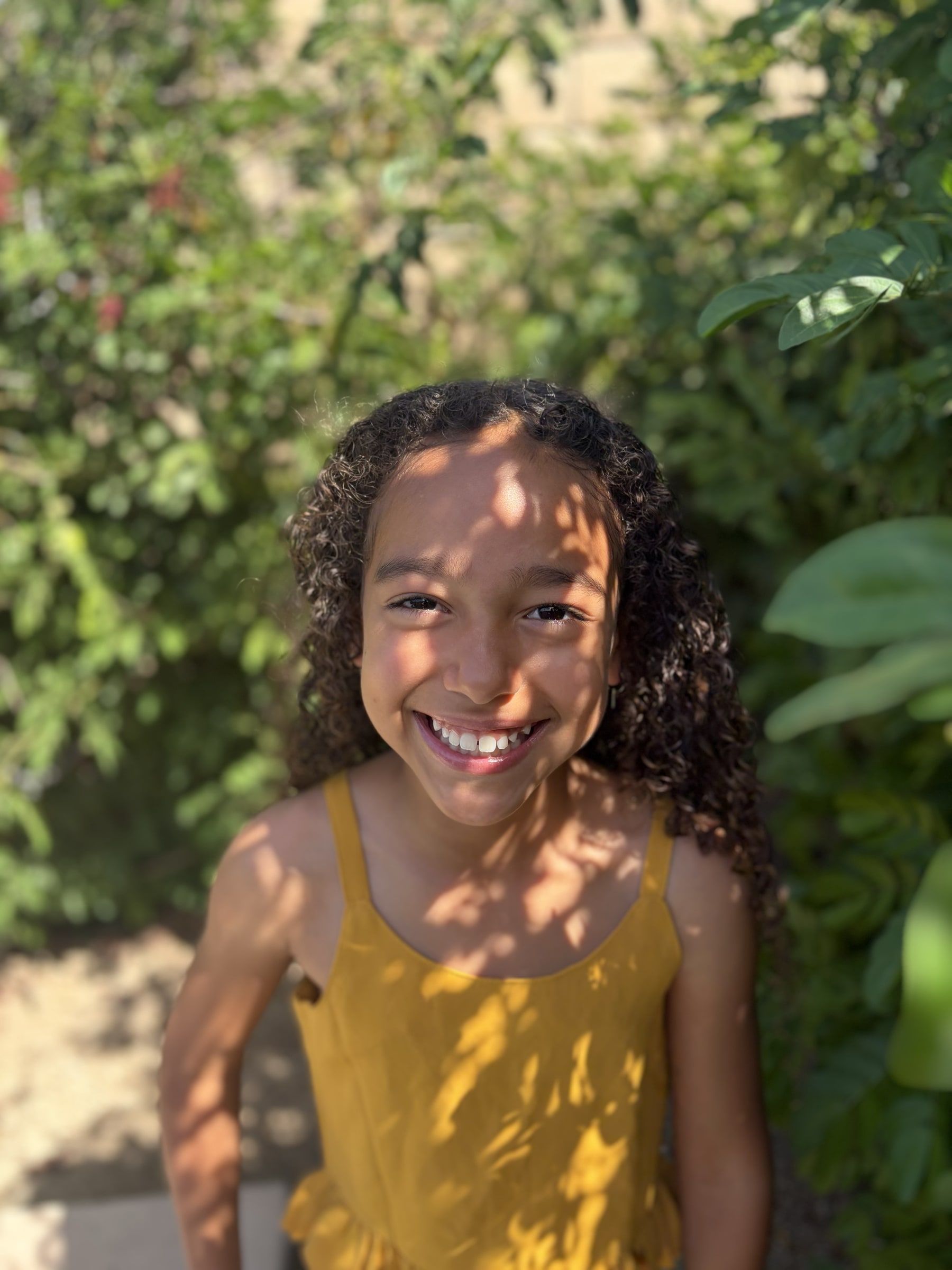 Niabelle smiling outside near bright pink flowers