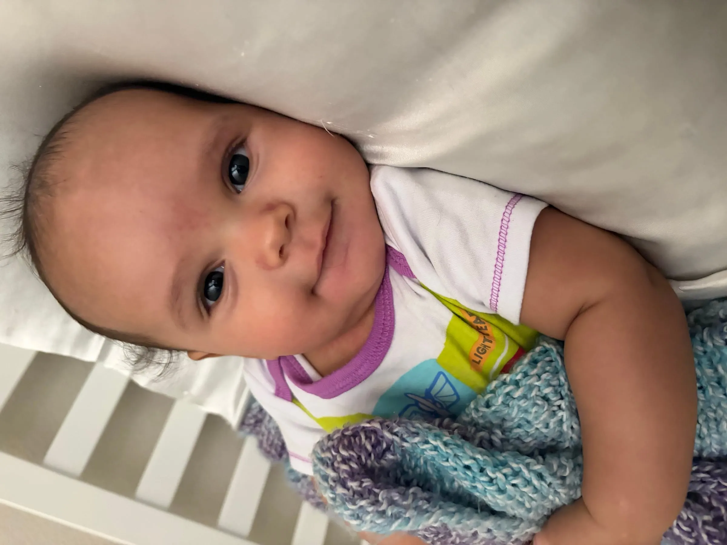 Noah awake in his crib under a soft blanket