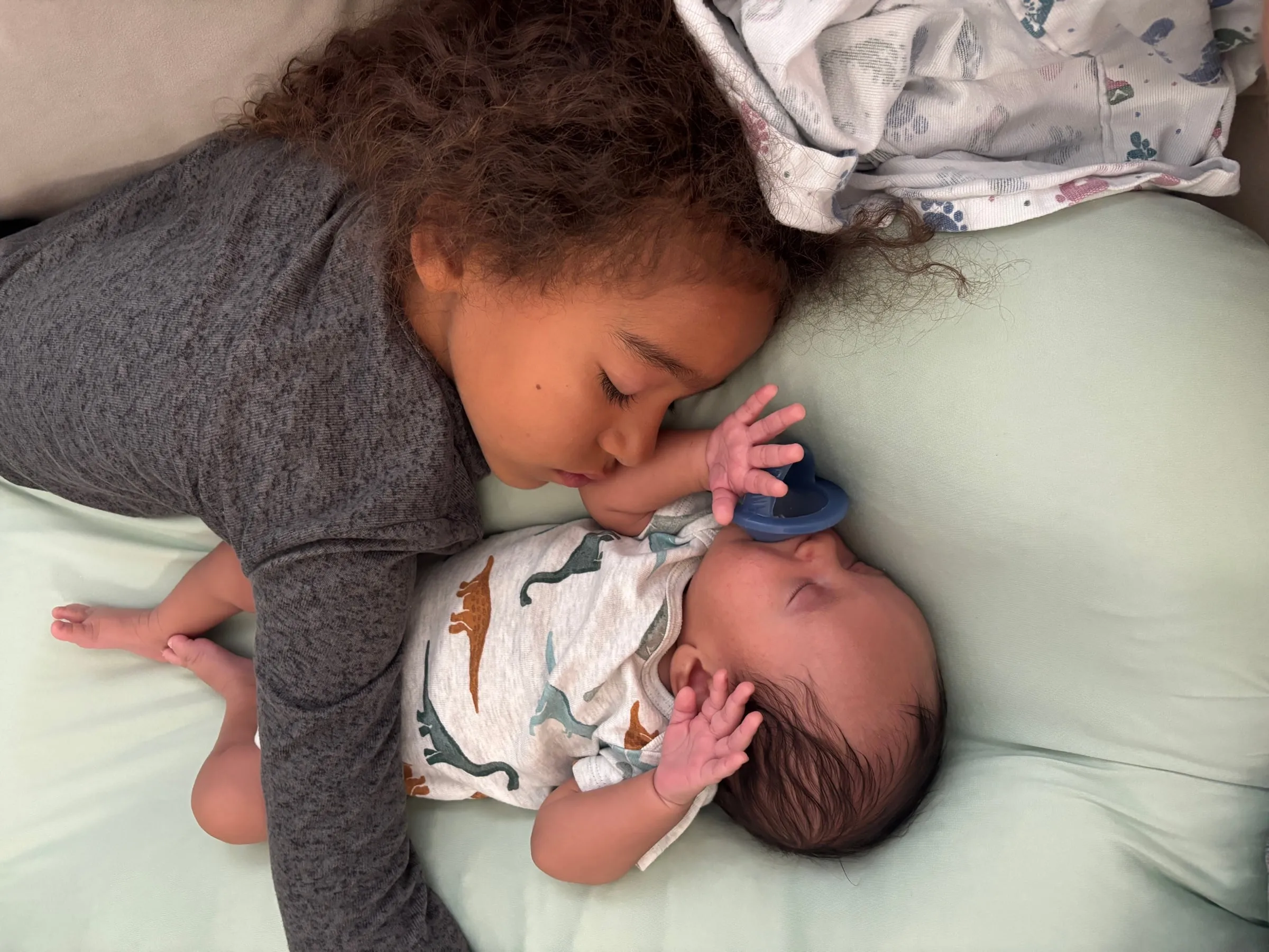 Nia sleeping beside Noah on a sage bed