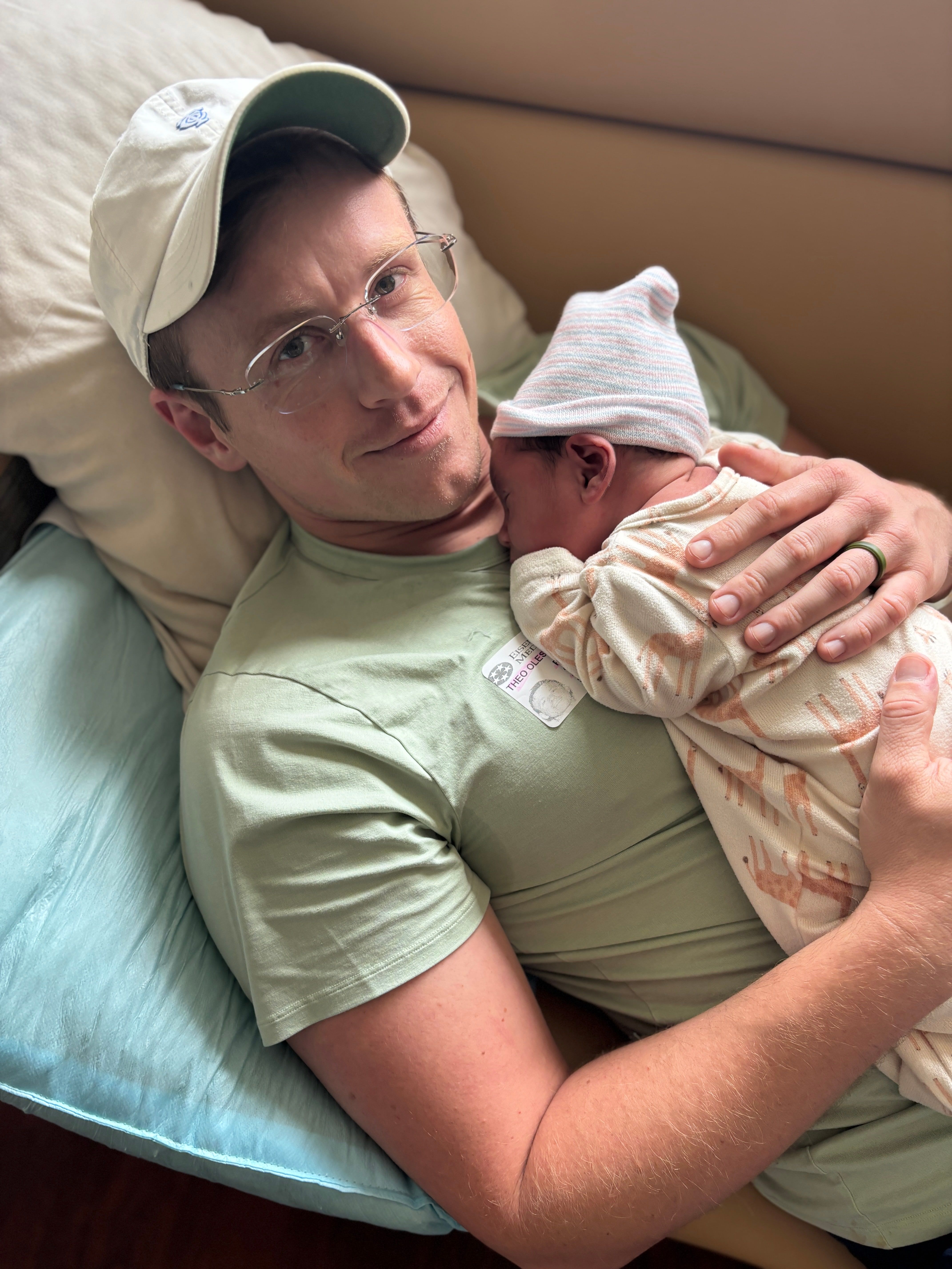 Theo lying down and holding newborn Noah