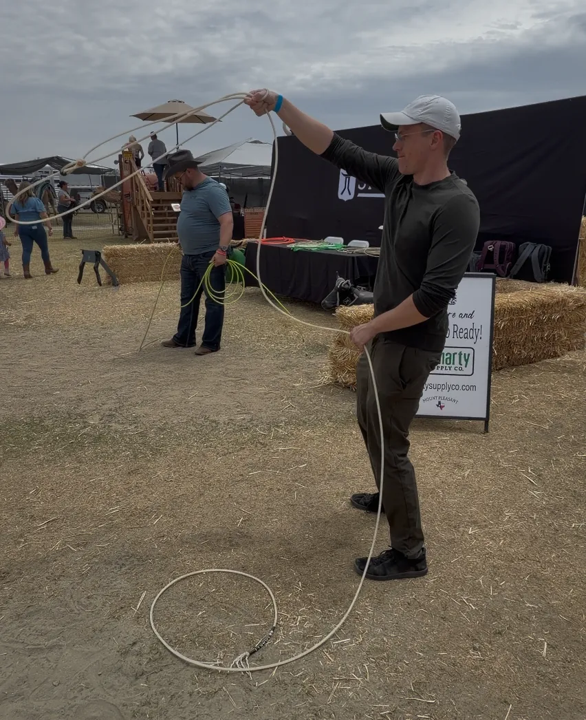 Theo attempting to lasso a target at a Desert Rodeo vendor booth, with the rope going nowhere near where it should